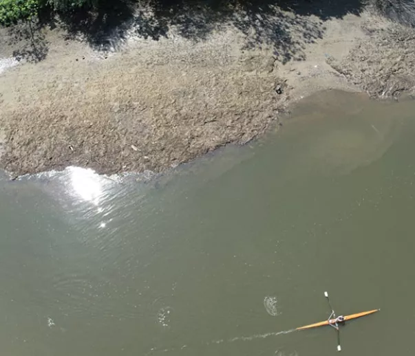 Drone footage of 'wet wipe island' with foreshore covered in wet wipes and kayaker rowing past 