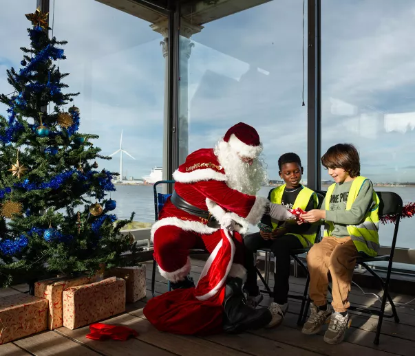 Santa with two children with a Christmas tree and the River Thames in the background