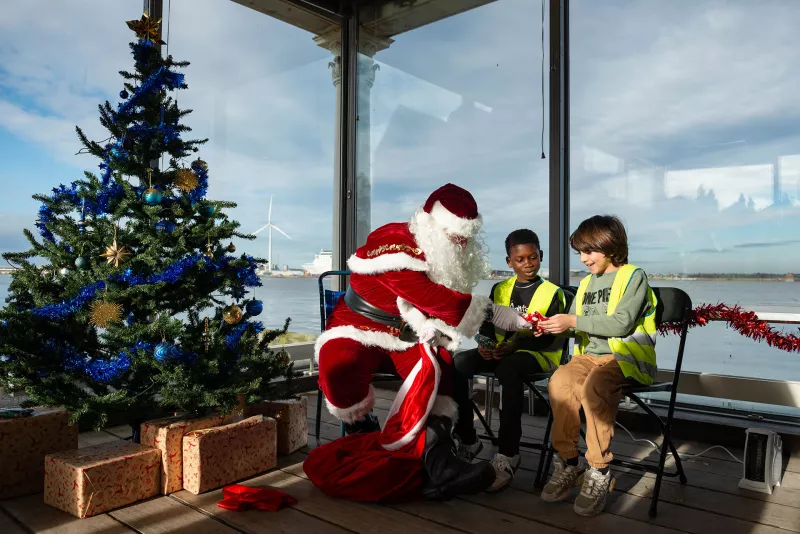 Santa with two children with a Christmas tree and the River Thames in the background